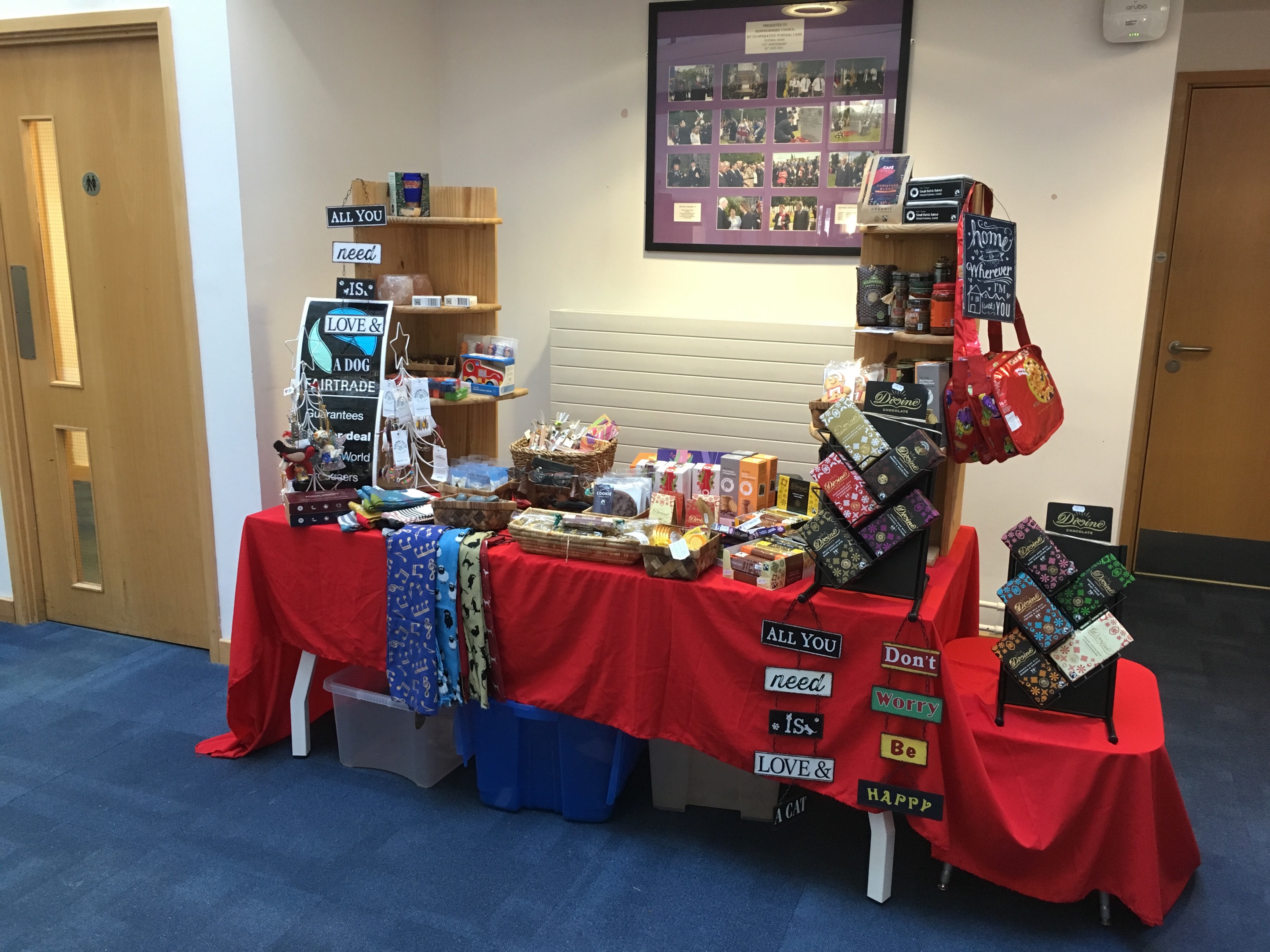 Stall displaying fair trade items including chocolate, scarves, biscuits and wall hangings